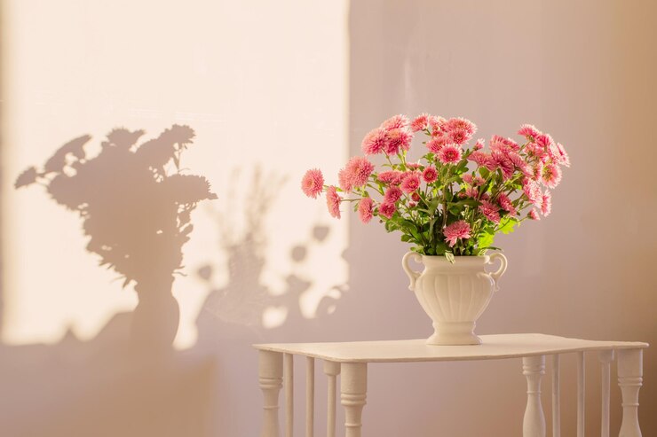 Pink chrysanthemums in white vase on white interior