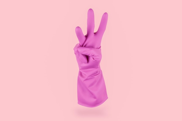 Pink cleaning glove counting three with his fingers on a pink background