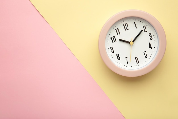 Pink clock on beige and pink background Top view