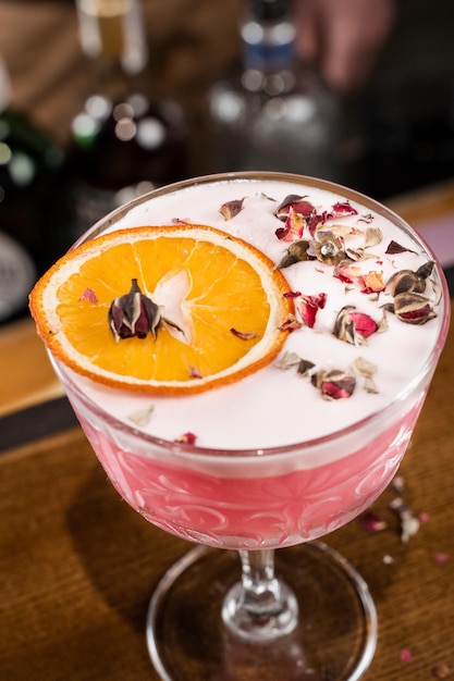 Pink Clover club alcoholic cocktail with roses decoration closeup at the bar Bartender mixes egg white lemon dry vermouth and gin to prepare the Clover club cocktail