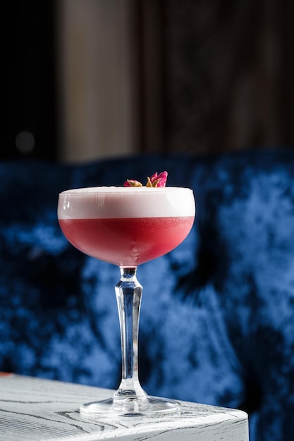 Pink Clover Club Cocktail in Coupe glas met laag schuim en bloem garnituur geïsoleerd op donkere achtergrond