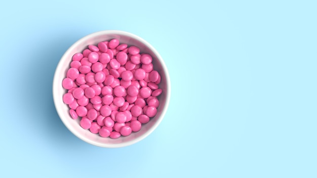 Pink coated chocolate candies in white bowl on blue background