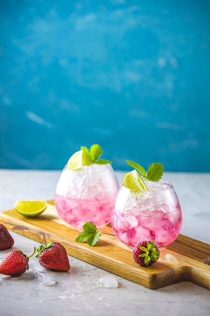 Pink cocktail with lime crushed ice strawberries and mint on the light background selective focus image copy spice for you text summer vacation and party concept