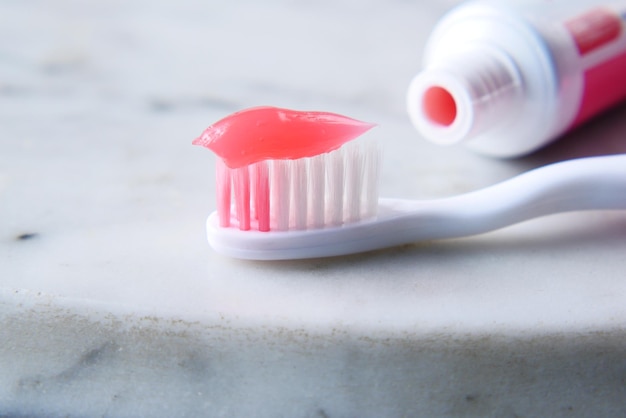 Pink color paste on a tooth brush on table
