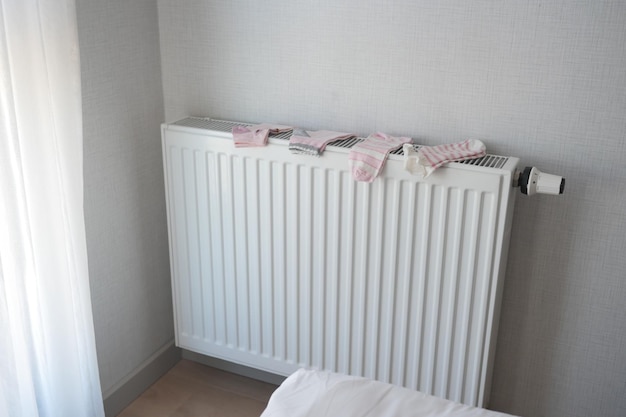 pink color socks drying on heating radiator