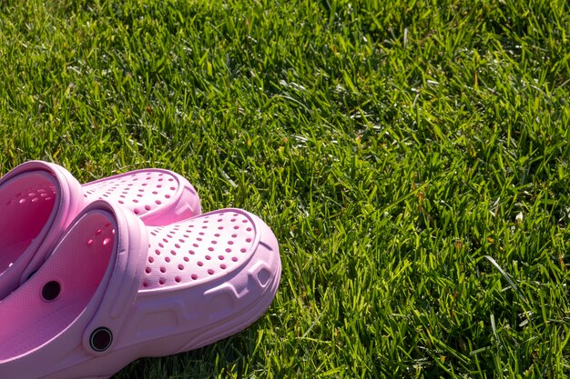 Pink comfortable flip-flops on a green grass.