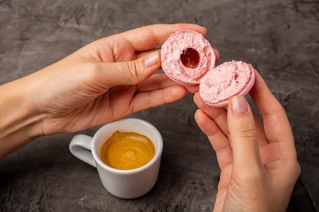 Pink cookie macaron is broken in half in female hands