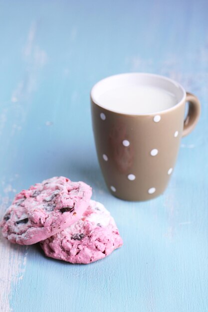 Pink cookies and cup with milk on table close-up