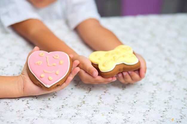 Pink Cookies in the form of a butterfly and heart lie on a children's hand