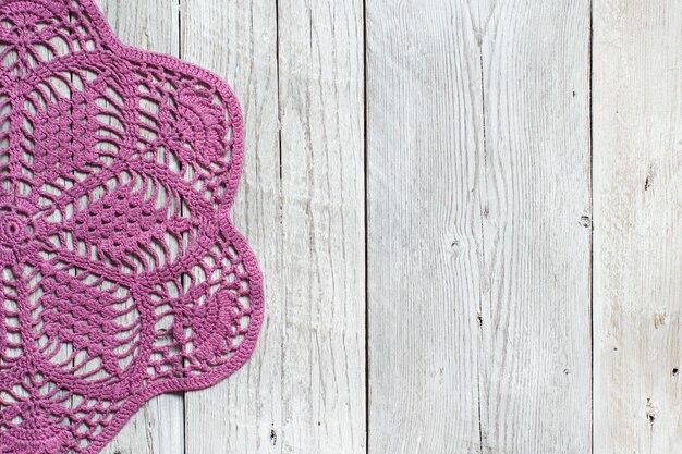 Pink crochet doily on the old wooden table