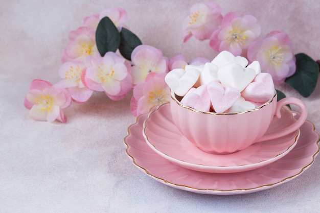 in a pink cup heart-shaped marshmallows and pink flowers