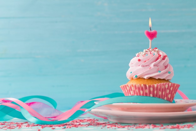 Pink cupcake on blue wooden table