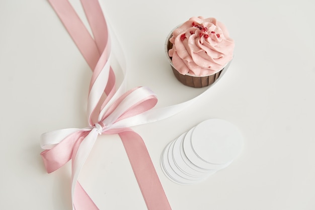 Photo pink cupcake on a white table with a pink bow