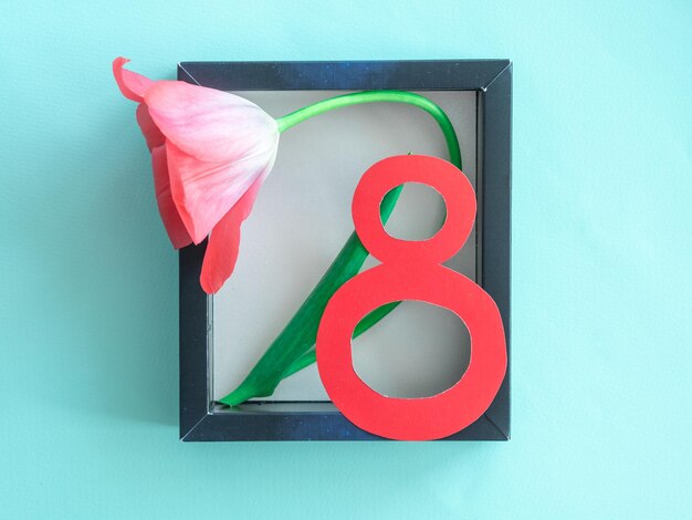 Photo pink delicate tulips in a cardboard frame and a spring creative card with the number 8 for women's d