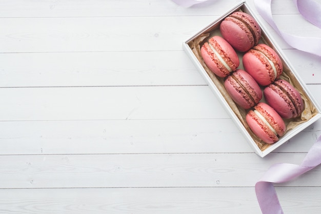 Pink dessert macaron or macaroons in a box on a white background with copy space.