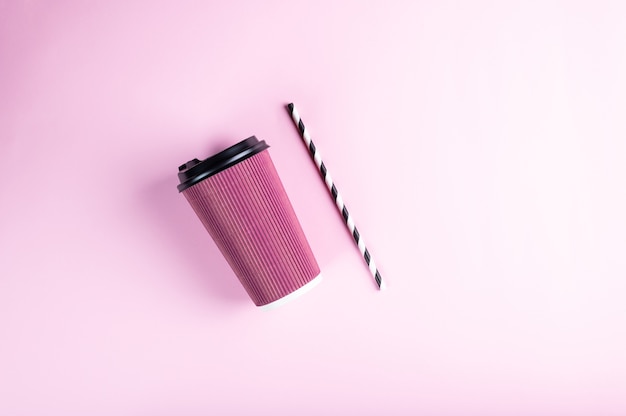 Pink disposable paper cup with striped paper straw