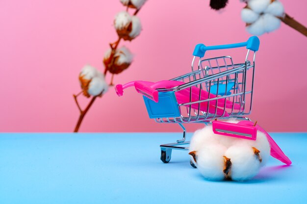 Pink disposable razors and cotton flower on blue paper