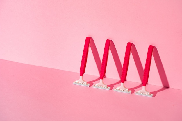 Pink disposable razors on pink background, copy space