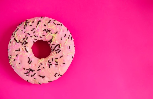 Pink donut on a bright pink background cheers up copy space