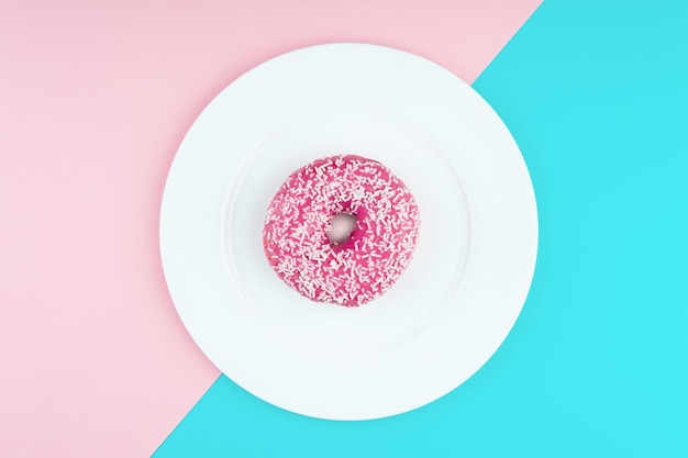 Pink donut on color background flat lay top view