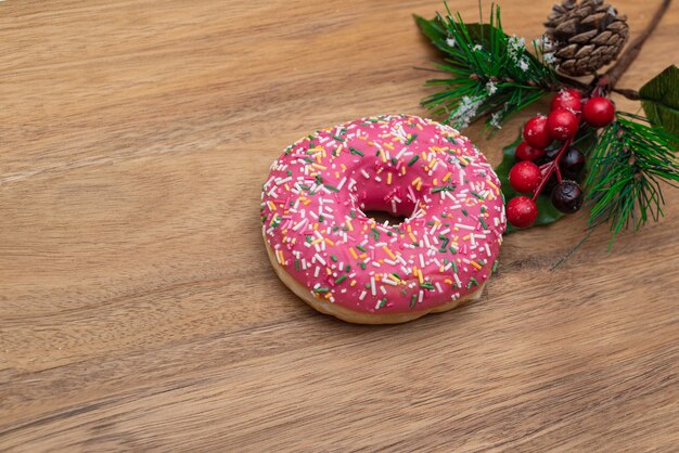 Розовый пончик в глазури и праздничная ветка сосны
