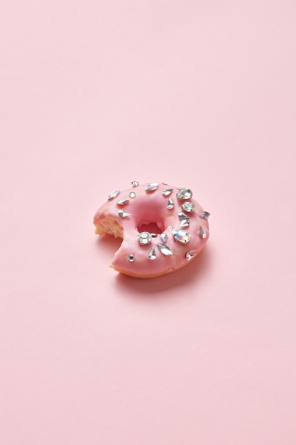 Photo a pink donut with silver glitter on a pink background
