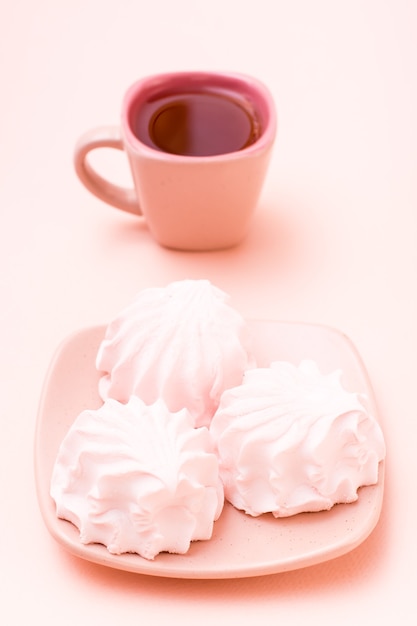 Pink drink in a coffee cup and marshmallows on a saucer.