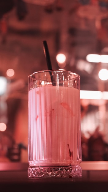 ストローが入ったピンクの飲み物がストローの入ったグラスの中にあります