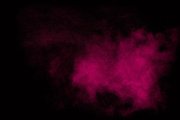 Pink dust particles splash on black background.Pink powder splash.