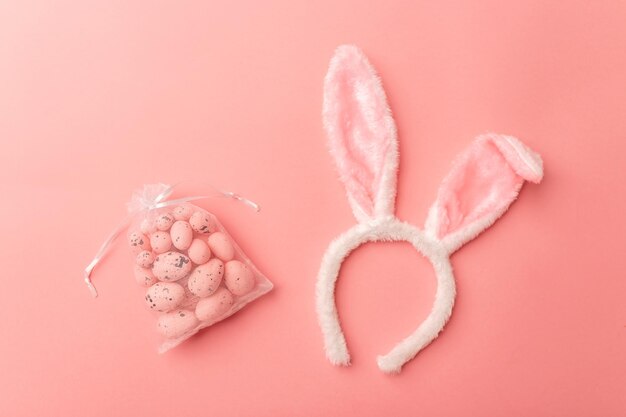 Pink Easter eggs and bunny toy ears lie on a pink background The concept of the Easter holiday