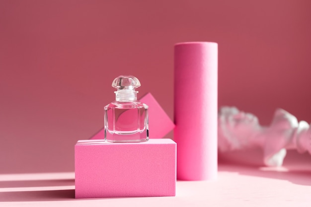 Pink eau de parfum in a glass bottle with pink pedestals and pink background