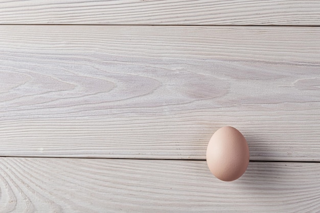 A pink egg in natural color on white wooden table