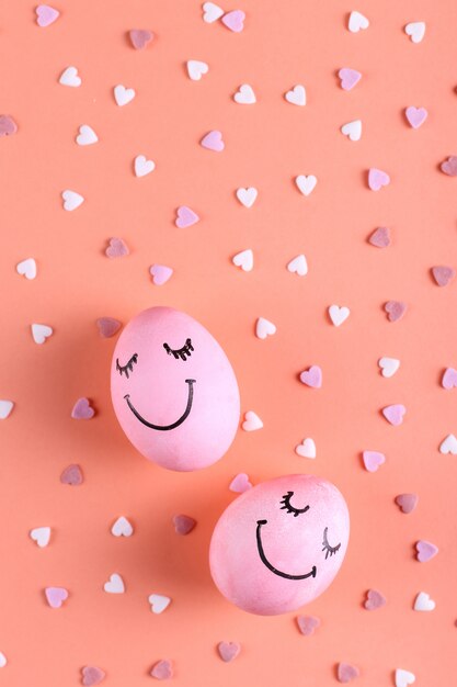 Foto uova rosa con sorrisi dipinti sullo sfondo con cuori, auguri di buona pasqua.