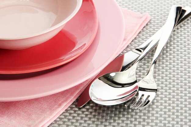 Photo pink empty plates with fork spoon and knife on a grey tablecloth