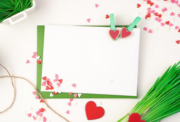 Розовый конверт, зеленый букет и сердца на светлом фоне.