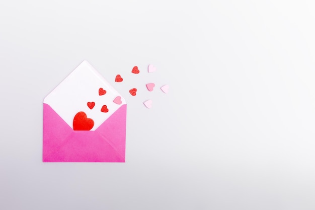 Pink envelope and hearts on a gray background The concept of Valentine39s day love dating and wedding Symbol of love letters Copy space flat lay