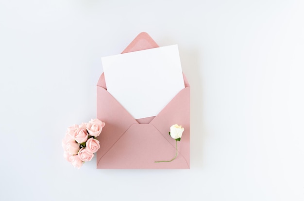 Pink envelope with card and roses on white background