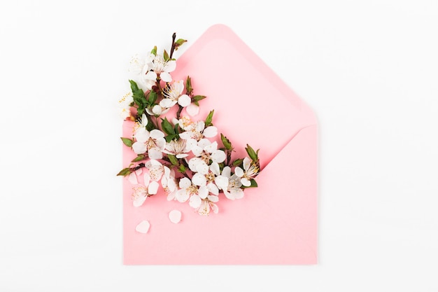 Pink envelope with a spring flower arrangement. Flat lay, top view.