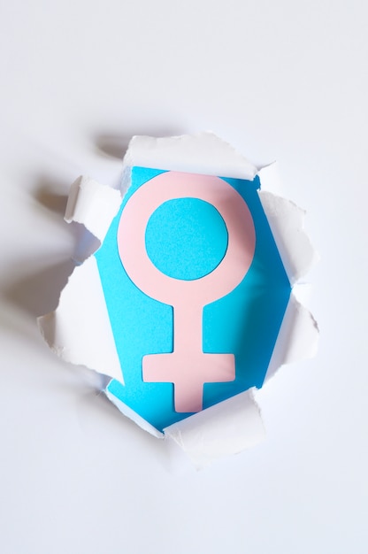 Pink female symbol on the blue sticking out of a hole in the white paper