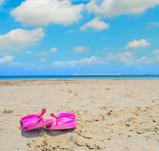 Pink flip flops on the sand in Sardinia Italy