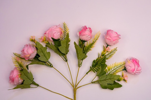 A pink flower arrangement with green leaves and a white background