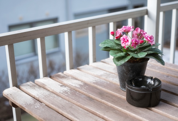 Pink flower with ceramic ashtray on wooden table at terrace