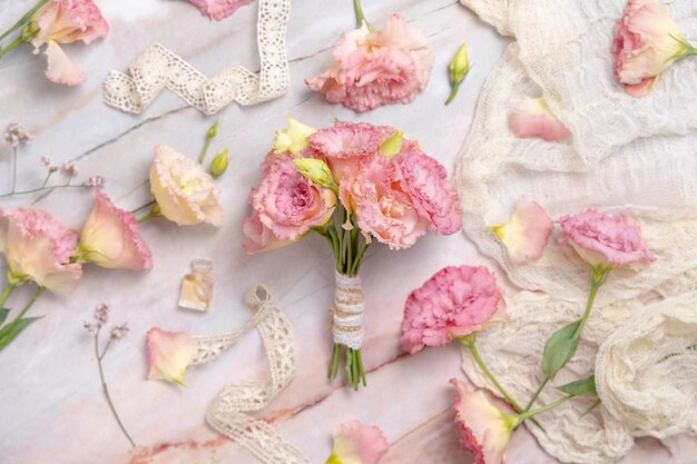 花とリボンが周りにある大理石のテーブルの上のピンクの花の花束、上面図。婚約の提案とバレンタインデーのギフトのコンセプト。