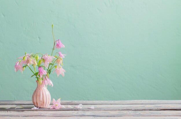 Pink flowers in pink vase on background green wall