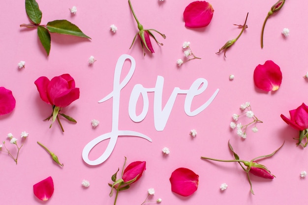 Pink flowers and text love on a light pink background top\
view