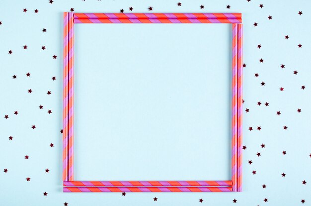 Photo pink frame from straw composition on blue background, party and celebration decoration.