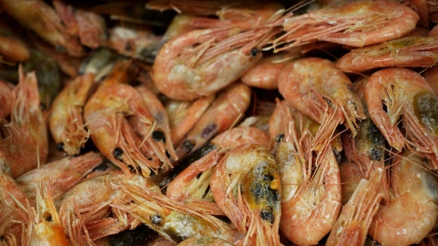 Pink fresh frozen shrimps with ice in a supermarket or fish shop Uncooked seafood close up background Fresh frozen prawns delicacies sea food concept close up