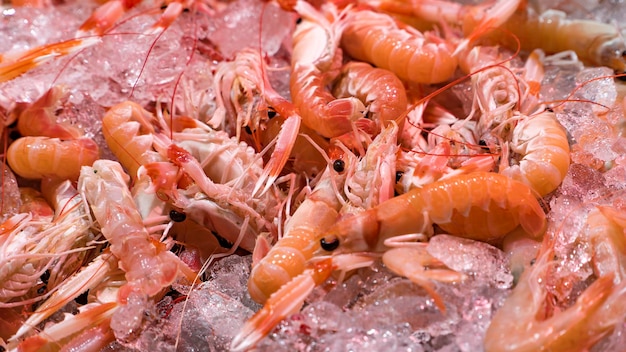 Pink fresh frozen shrimps with ice in a supermarket or fish shop. Uncooked seafood close up background. Fresh frozen prawns, delicacies, sea food concept, close up.