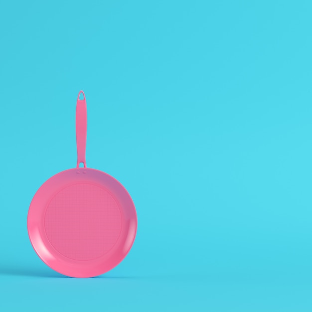 Pink frying pan on bright blue background