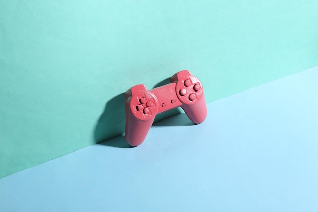 トレンディな影と青の背景にピンクのゲームパッド 創造的なレイアウト ミニマルな静物